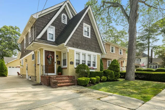 a view of a brick house with many windows plants and large tree