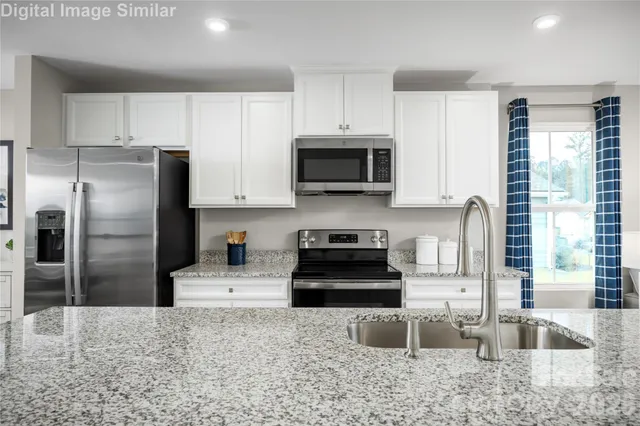 a kitchen with granite countertop a refrigerator a stove a sink a window and cabinets