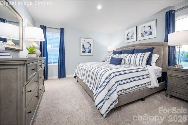 a spacious bedroom with a bed and a lamp on dresser