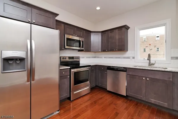 a kitchen with granite countertop stainless steel appliances a sink a refrigerator a stove a microwave and cabinets