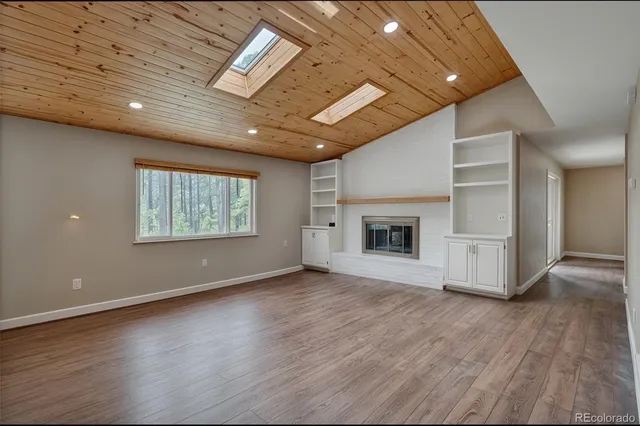 an empty room with wooden floor fireplace and windows