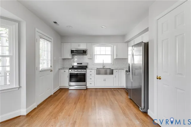 a kitchen with wooden floors appliances and window