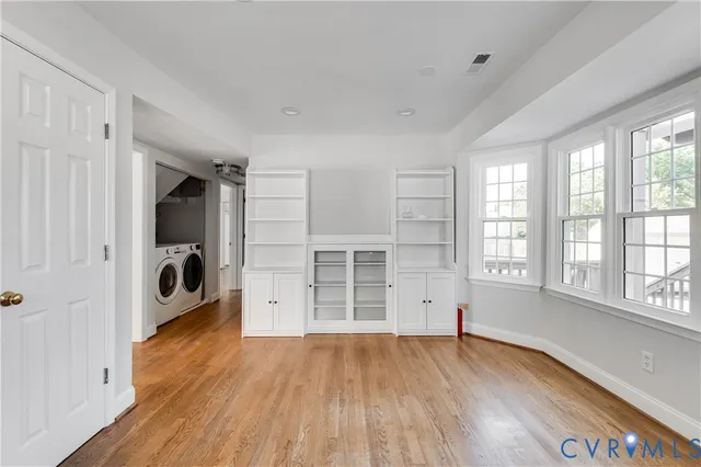 an empty room with wooden floor closet and windows