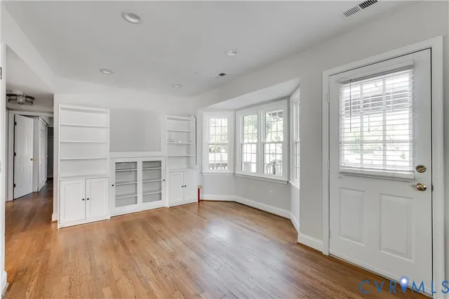 an empty room with wooden floor and windows