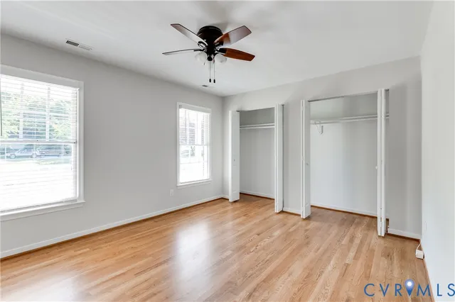 a view of empty room with wooden floor and fan