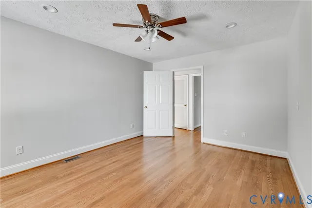 an empty room with wooden floor and ceiling fan