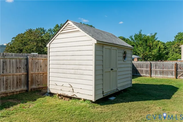 a view of backyard with small cabin and wooden fencing