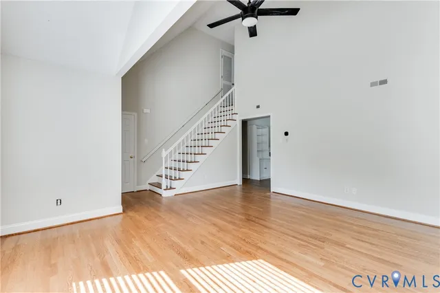 a view of an empty room with wooden floor and stairs
