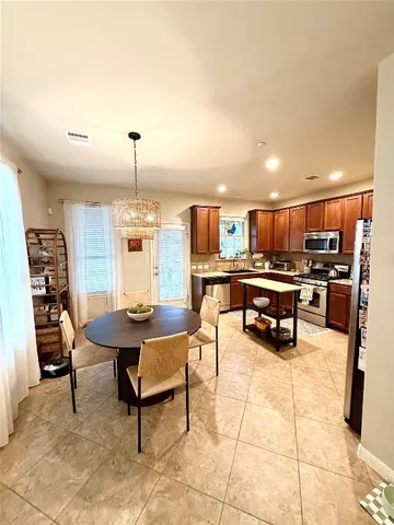 a kitchen with stainless steel appliances kitchen island granite countertop a table chairs and a refrigerator