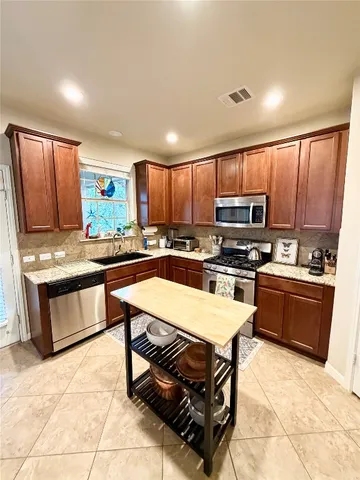 a kitchen with stainless steel appliances granite countertop a stove refrigerator sink and microwave