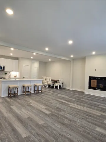 a view of an empty room with kitchen and window