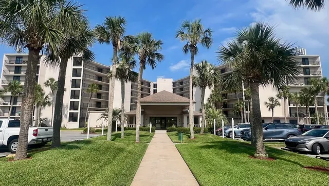 a view of a house with a yard and palm trees