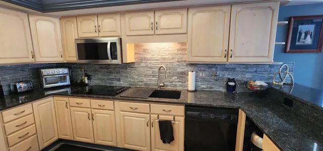 a kitchen with granite countertop white cabinets and black appliances