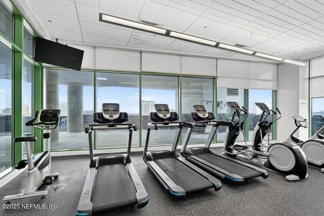 a living room with furniture a floor to ceiling window and a flat screen tv