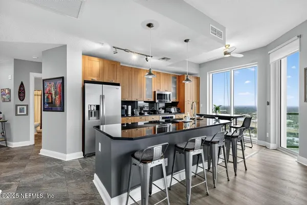 a kitchen with stainless steel appliances kitchen island granite countertop a table chairs and a refrigerator