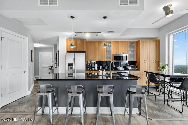 a living room with furniture floor to ceiling window hardwood floor and a flat screen tv