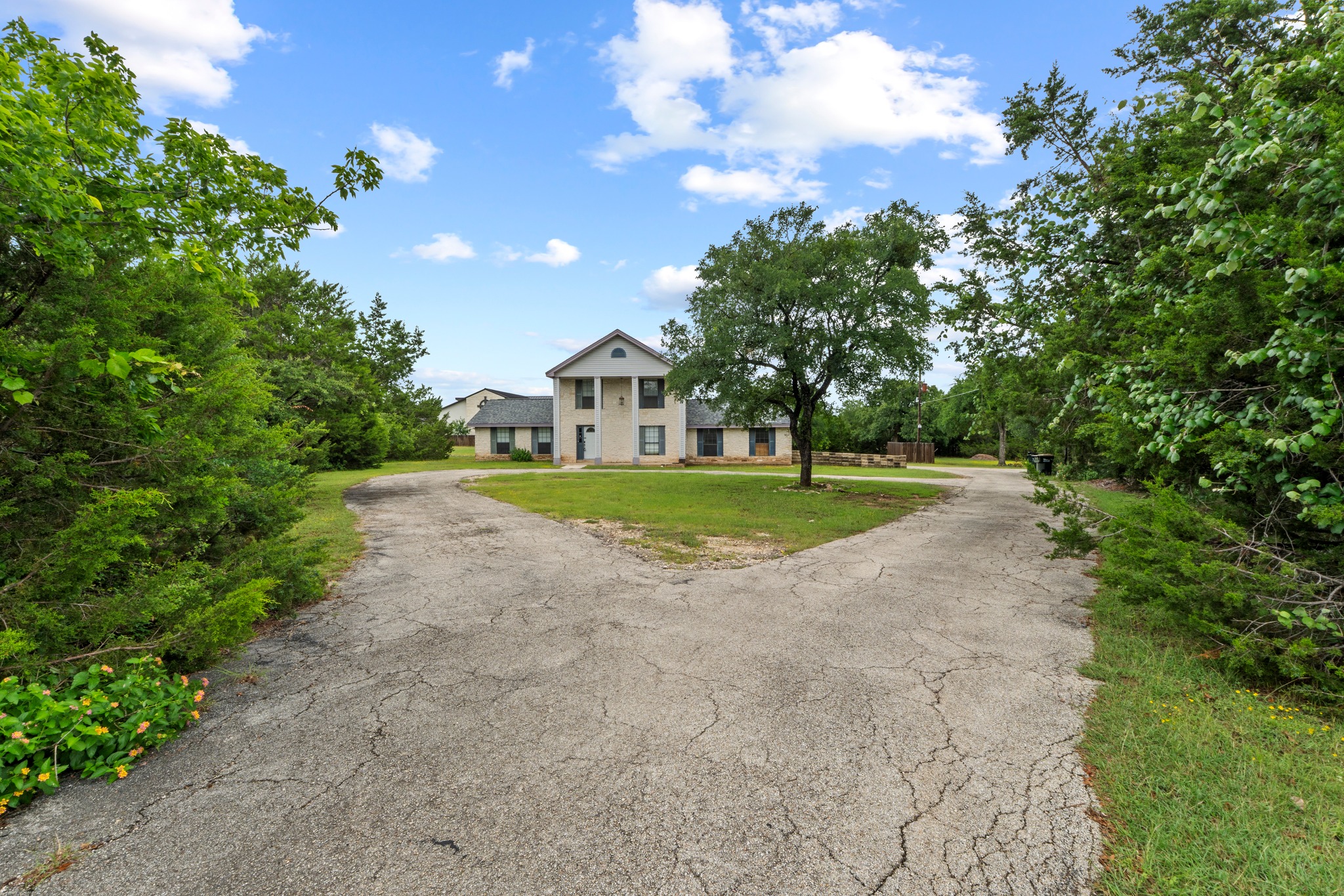 205 Sedro Trail Georgetown, TX 78633 - Photo 11 of 32 A traditional home with a split driveway offers privacy amidst mature trees and green landscaping.