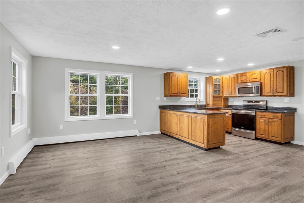 59 Molasses Hill Road Brookfield, MA 01506 - Photo 32 of 42 a large kitchen with stainless steel appliances granite countertop a stove a sink dishwasher a microwave oven with cabinets and wooden floor