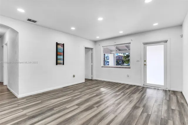 a view of empty room with wooden floor and window