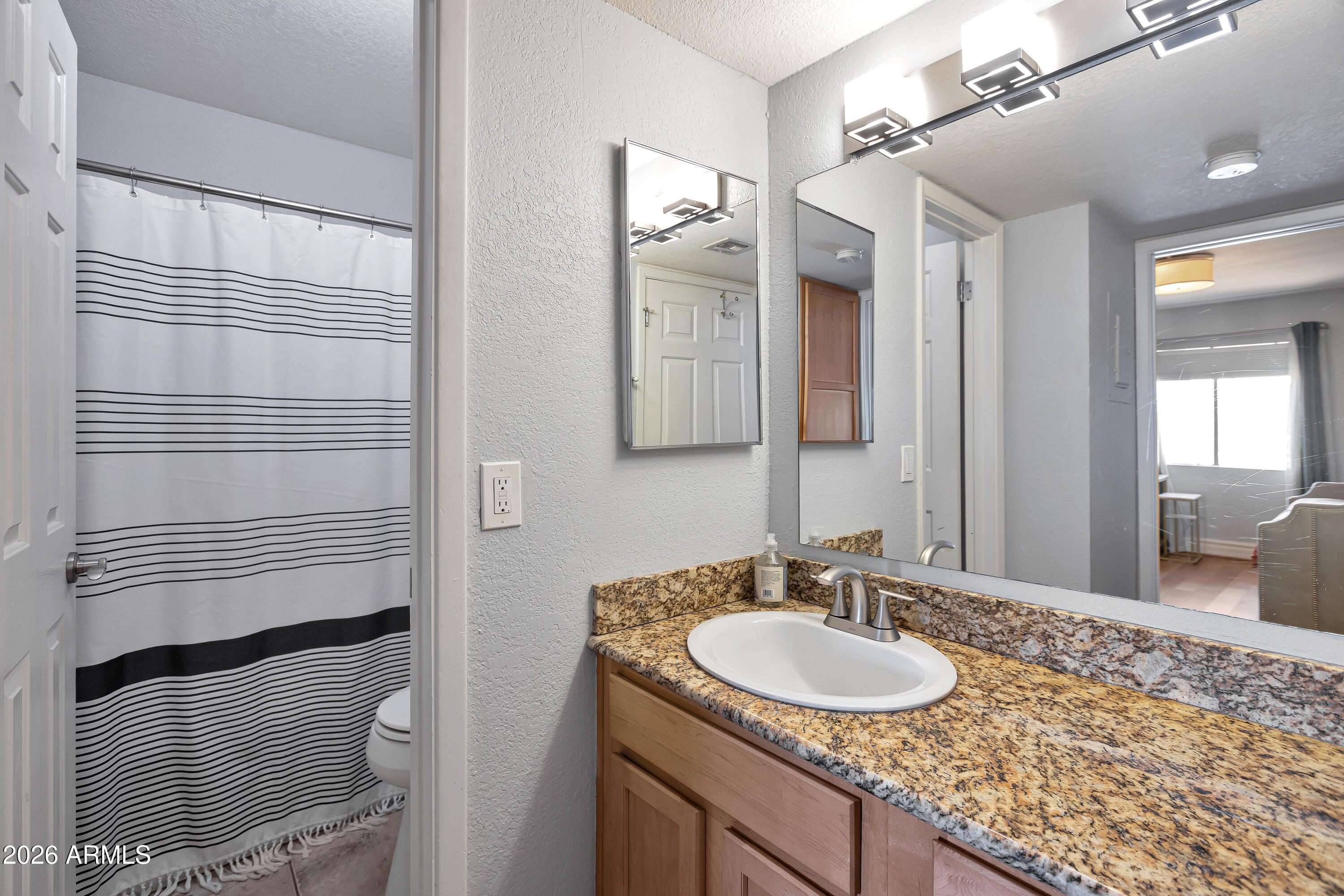 3825 East Camelback Road, Unit 218 Phoenix, AZ 85018 - Photo 19 of 28 a bathroom with a granite countertop sink and a mirror