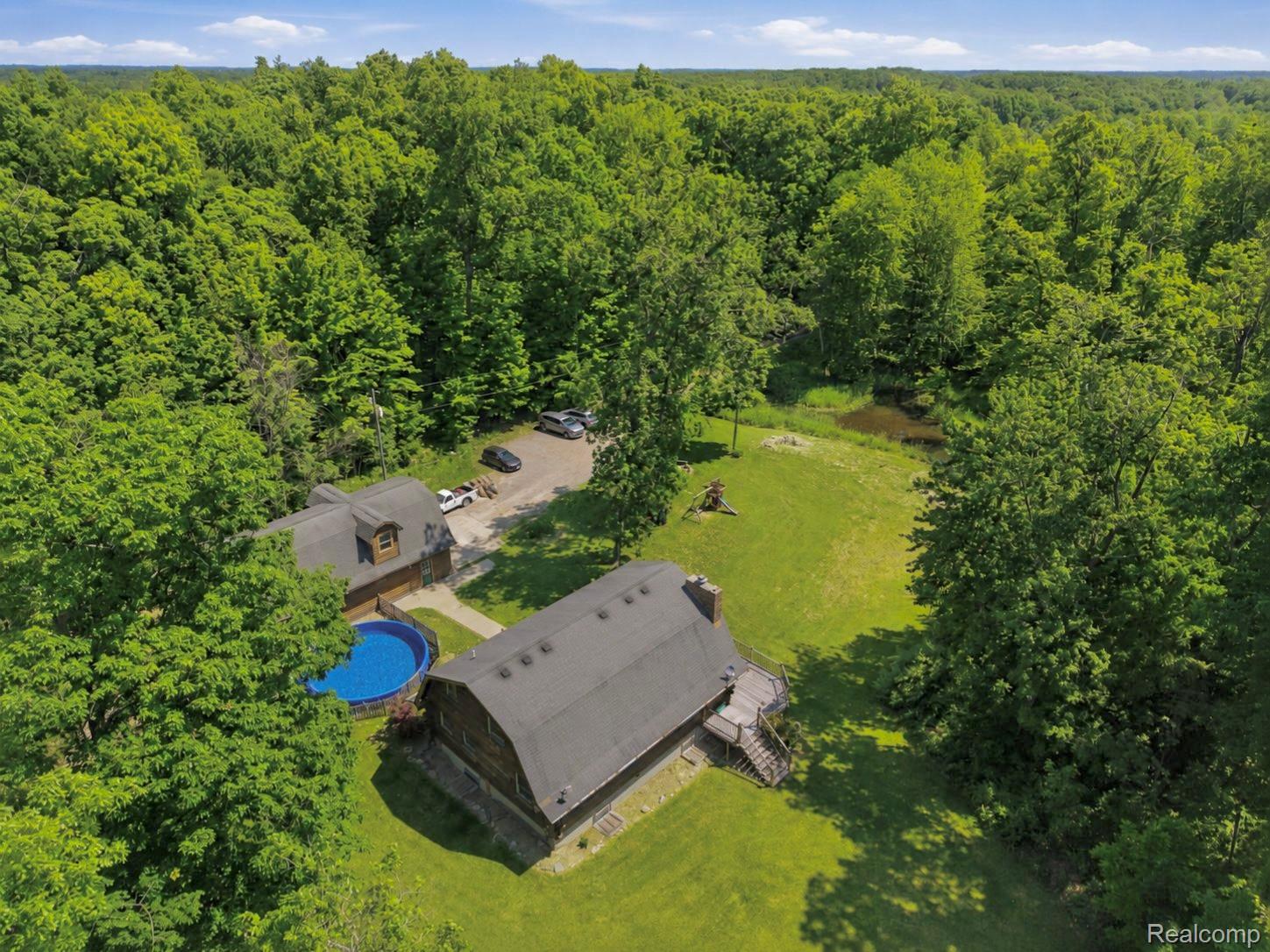 14830 Sheridan Road Byron, MI 48418 - Photo 74 of 74 Expansive wooded property featuring two residential structures, a circular above-ground pool, and a private driveway
