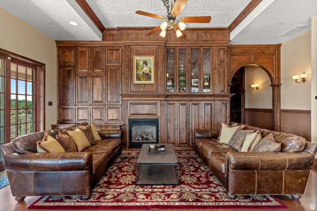 5615 East Eight Mile Gap Road Kanab, UT 84741 - Photo 6 of 81 Living area with wooden walls, a glass covered fireplace, an ornate ceiling, wood finished floors, and arched walkways