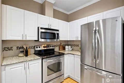 a kitchen with stainless steel appliances granite countertop white cabinets a refrigerator and a stove top oven