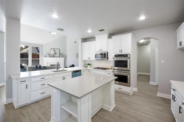 a large kitchen with stainless steel appliances sink a large counter top space and cabinets