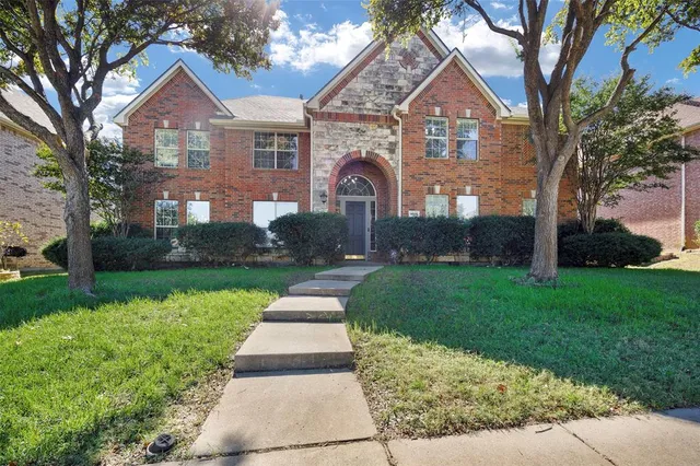 a front view of a house with a yard and garden