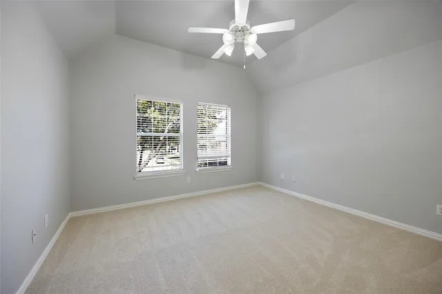 an empty room with chandelier fan and windows