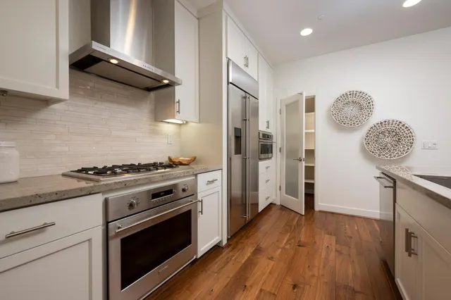 a kitchen with stainless steel appliances kitchen island granite countertop a dining table chairs and a refrigerator