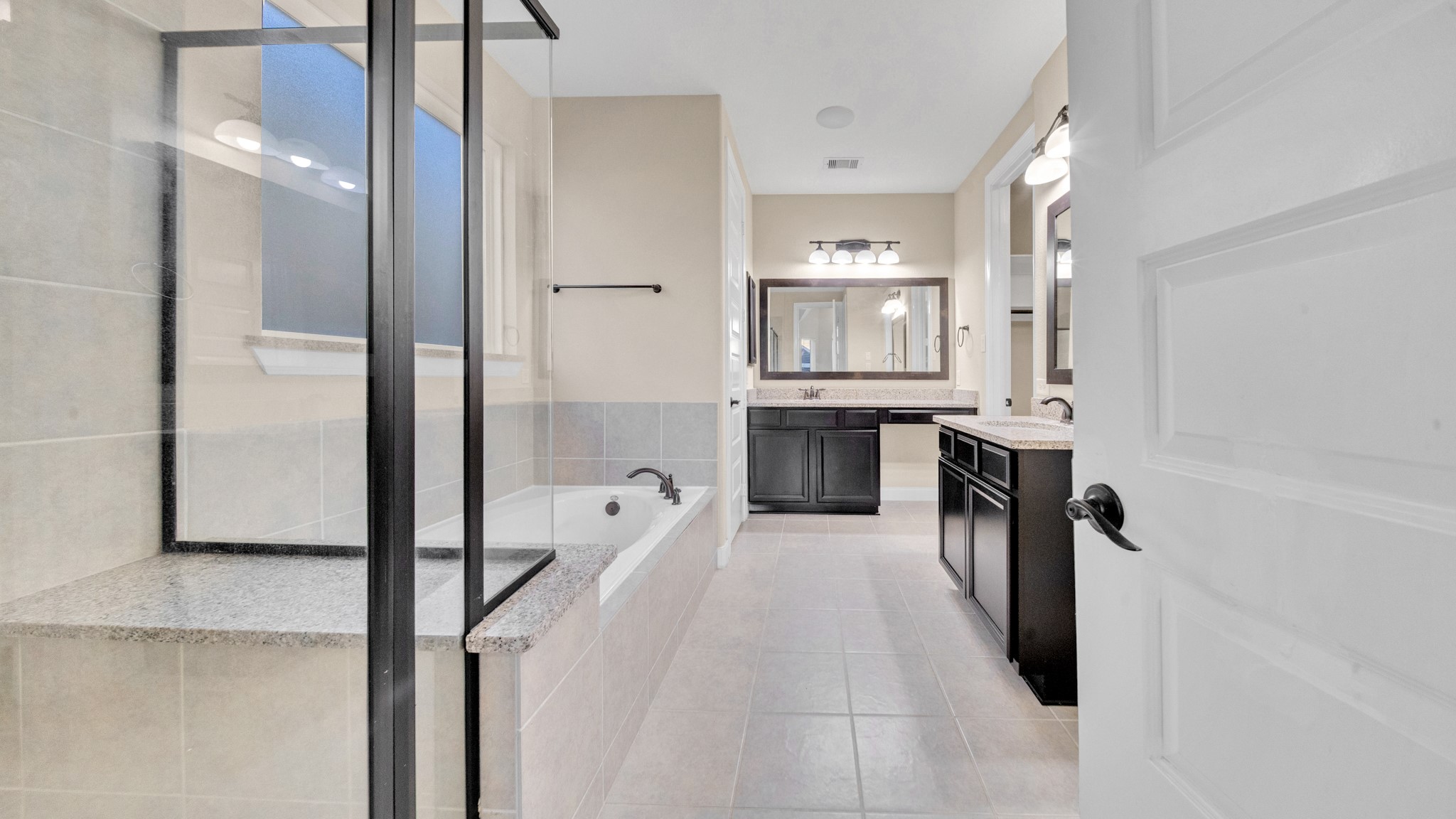 18118 Berry Garden Lane Spring, TX 77379 - Photo 19 of 45 Luxurious primary bathroom with separate vanities, granite counters, soaking tub, and a large glass-enclosed shower.