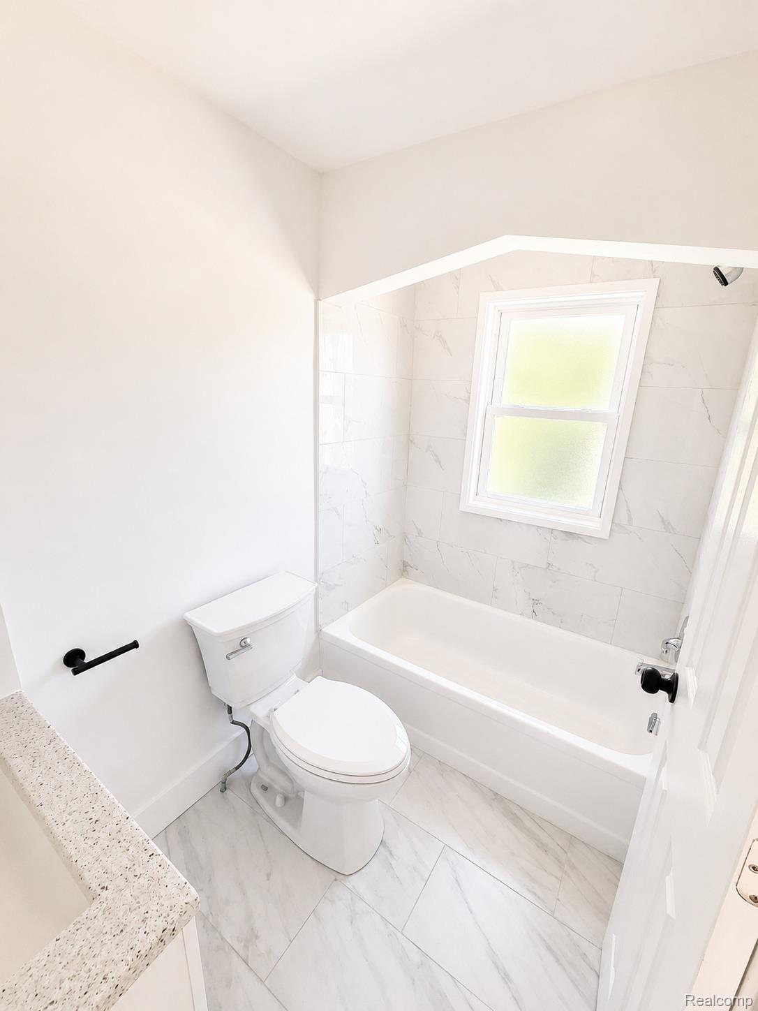 20024 Meyers Road Detroit, MI 48235 - Photo 12 of 16 Bathroom featuring a white bathtub, ceramic tile shower surround, and a coordinating tile floor