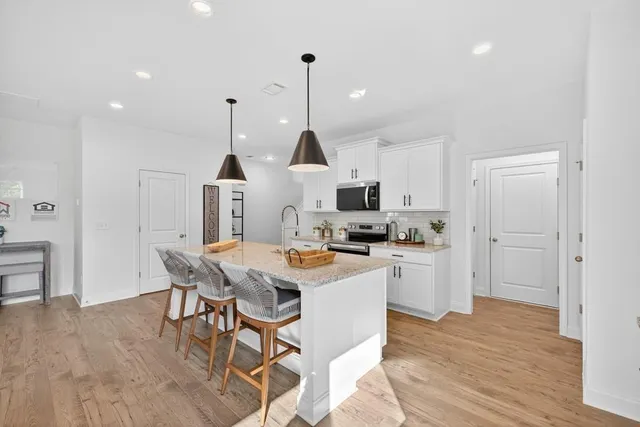 a kitchen with stainless steel appliances granite countertop a sink a stove and a wooden floor