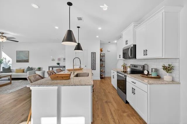 a kitchen with granite countertop a sink a stove and chairs