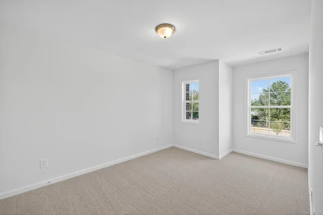 a view of an empty room with a window and chandelier fan