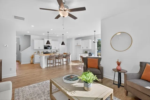 a living room with furniture kitchen view and a chandelier