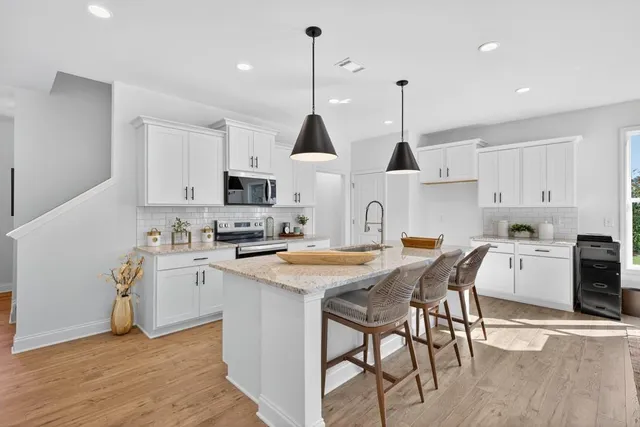 a kitchen with stainless steel appliances kitchen island granite countertop a sink a stove a dining table and chairs