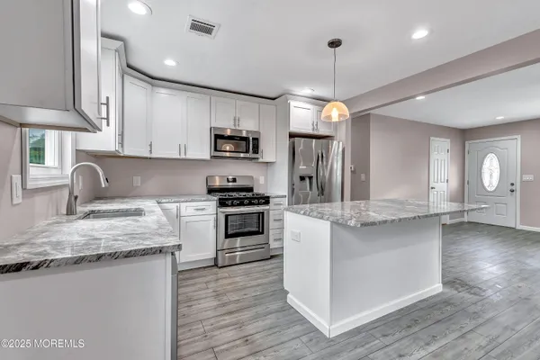 a kitchen with kitchen island granite countertop a sink cabinets and stainless steel appliances