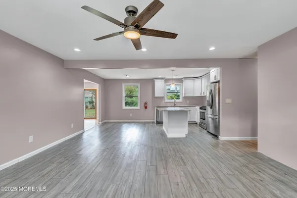 a view of a kitchen and an empty room with wooden floor and a window