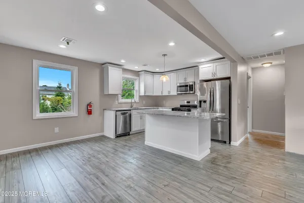 a kitchen with white cabinets and wooden floor