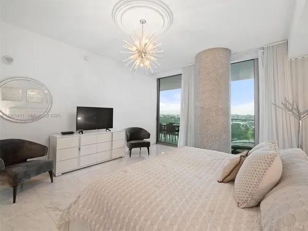 a bedroom with a bed a mirror and a large window