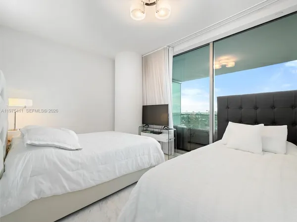 a bedroom with two beds and a large window