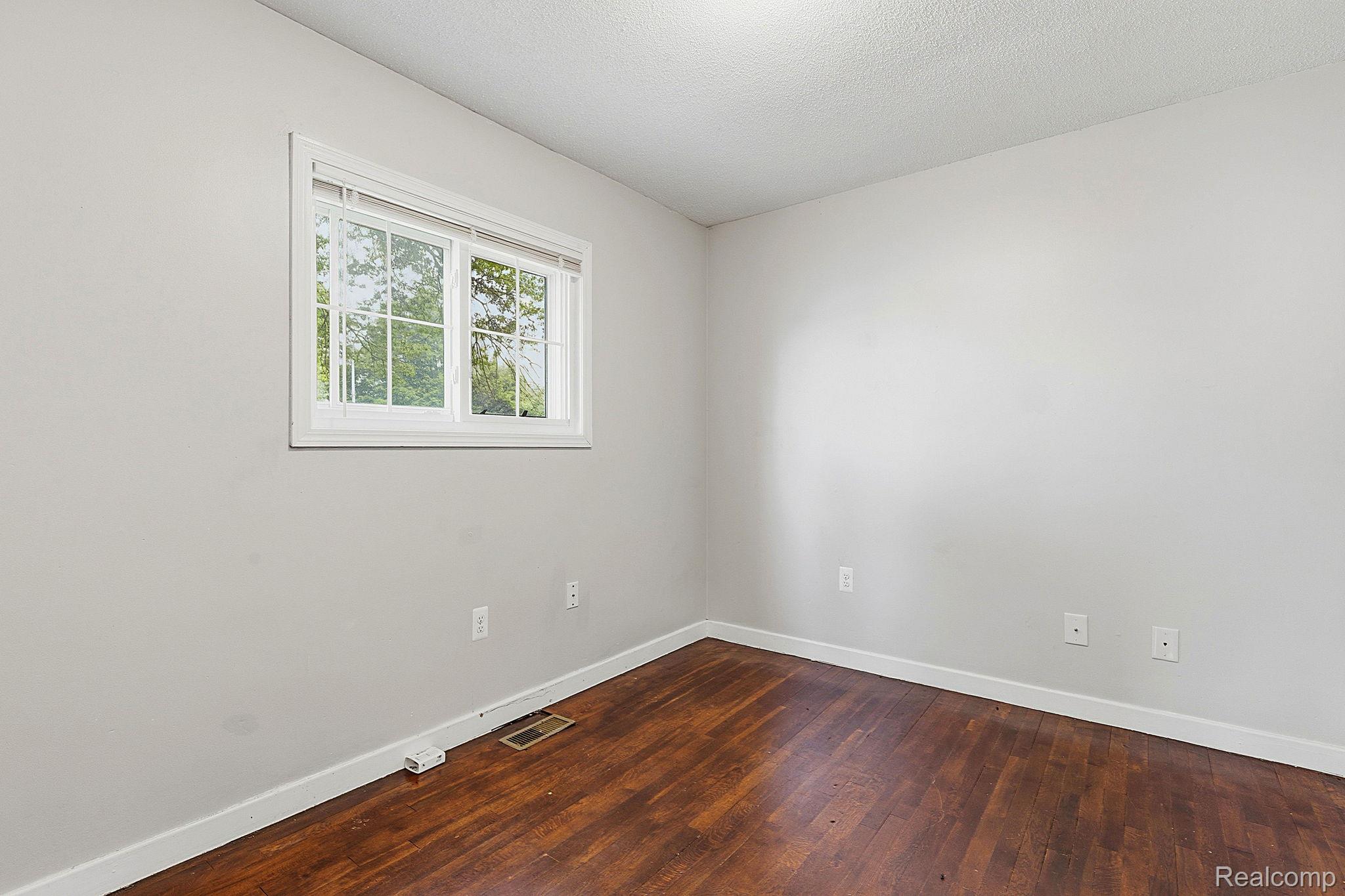 5852 Beech Daly Road Taylor, MI 48180 - Photo 17 of 29 Room featuring wood-finish flooring, light gray walls, white trim, and a white-framed window