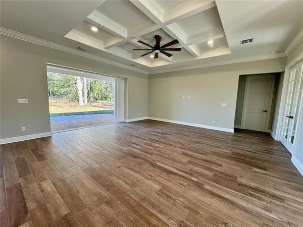 an empty room with wooden floor ceiling fan and windows