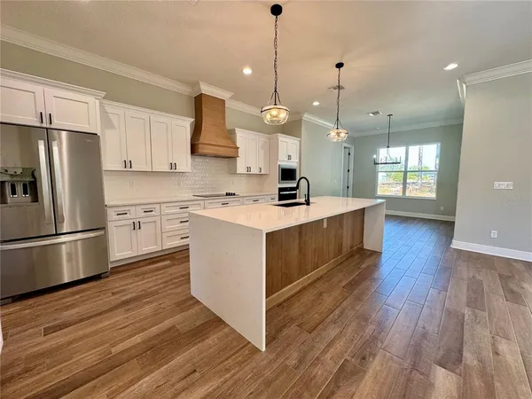 a kitchen with stainless steel appliances granite countertop a sink a stove a refrigerator and island with wooden floor