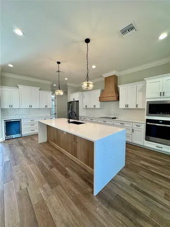 a large kitchen with stainless steel appliances kitchen island granite countertop a stove a sink dishwasher and a white countertops with wooden floor