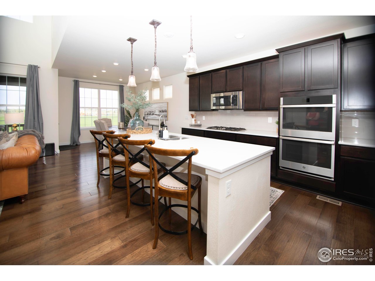 7086 Thunderview Drive Timnath, CO 80547 - Photo 11 of 38 a kitchen with stainless steel appliances kitchen island granite countertop a table chairs and a refrigerator