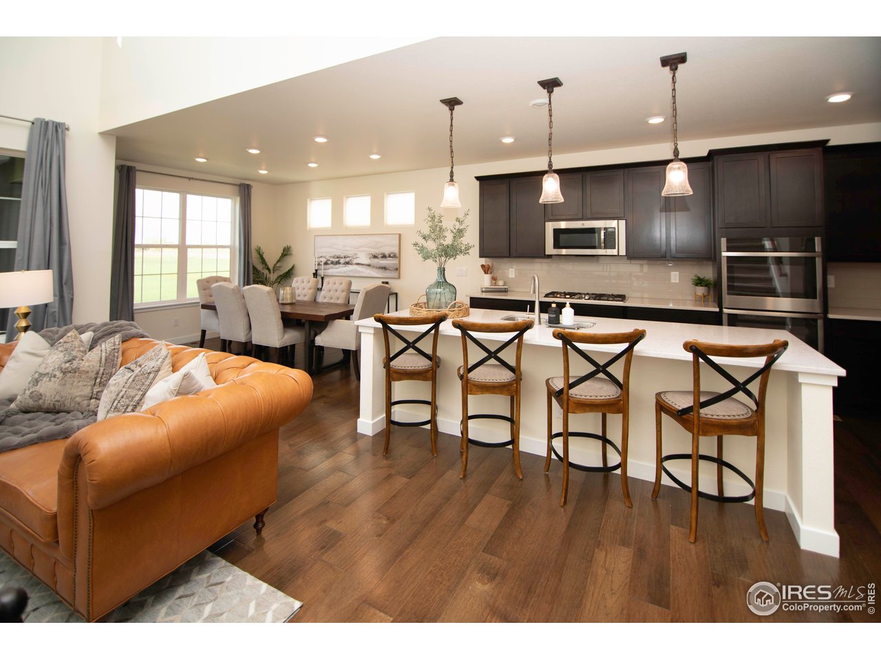 7086 Thunderview Drive Timnath, CO 80547 - Photo 12 of 38 a living room with stainless steel appliances kitchen island granite countertop furniture and a wooden floor
