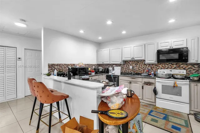 a kitchen with stainless steel appliances kitchen island granite countertop a stove a sink a dining table and chairs